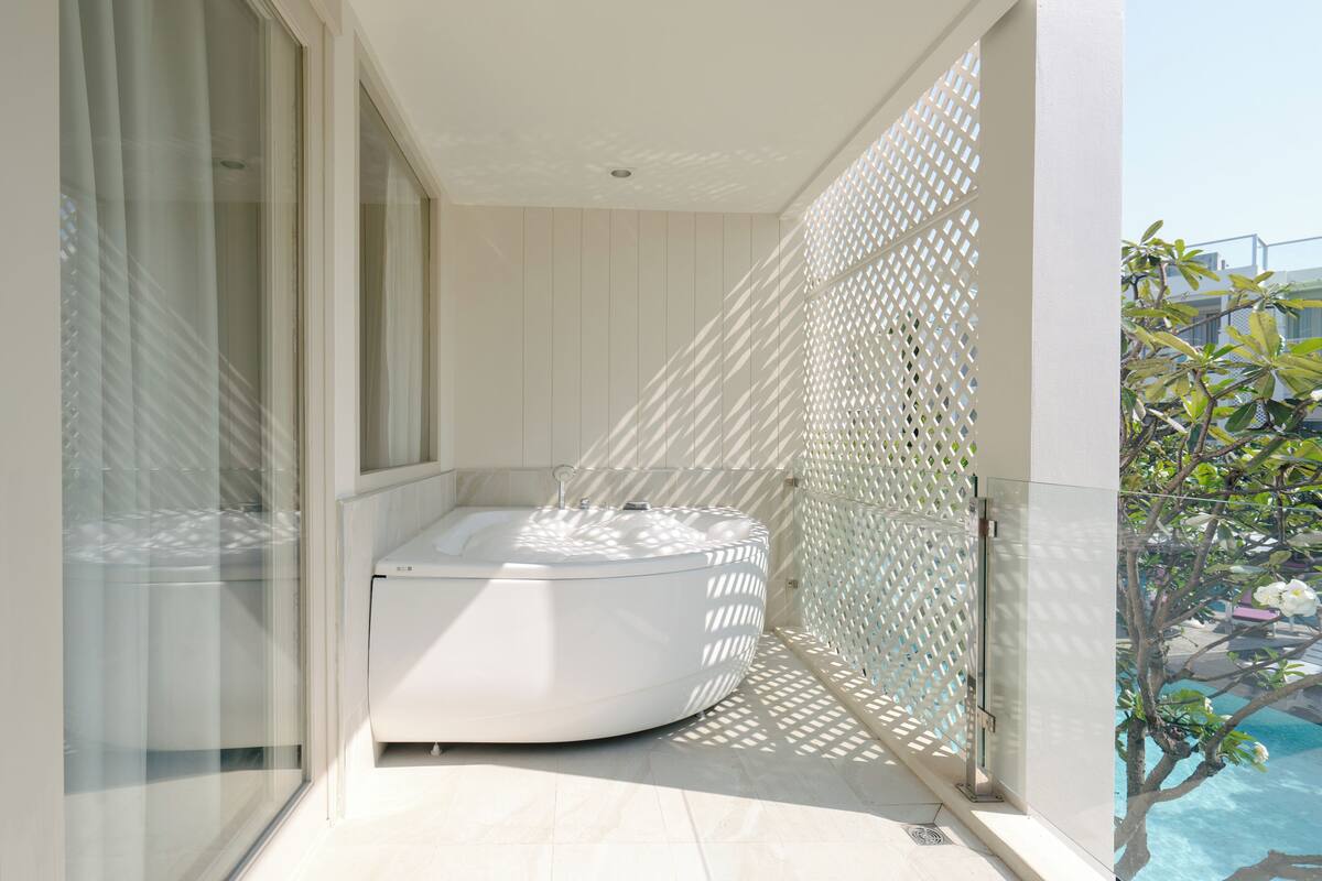 Une salle de bain moderne avec une baignoire sur pieds, une douche à parois de verre et une vue sur une piscine.