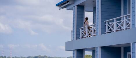 A blue building with a balcony overlooking a body of water.