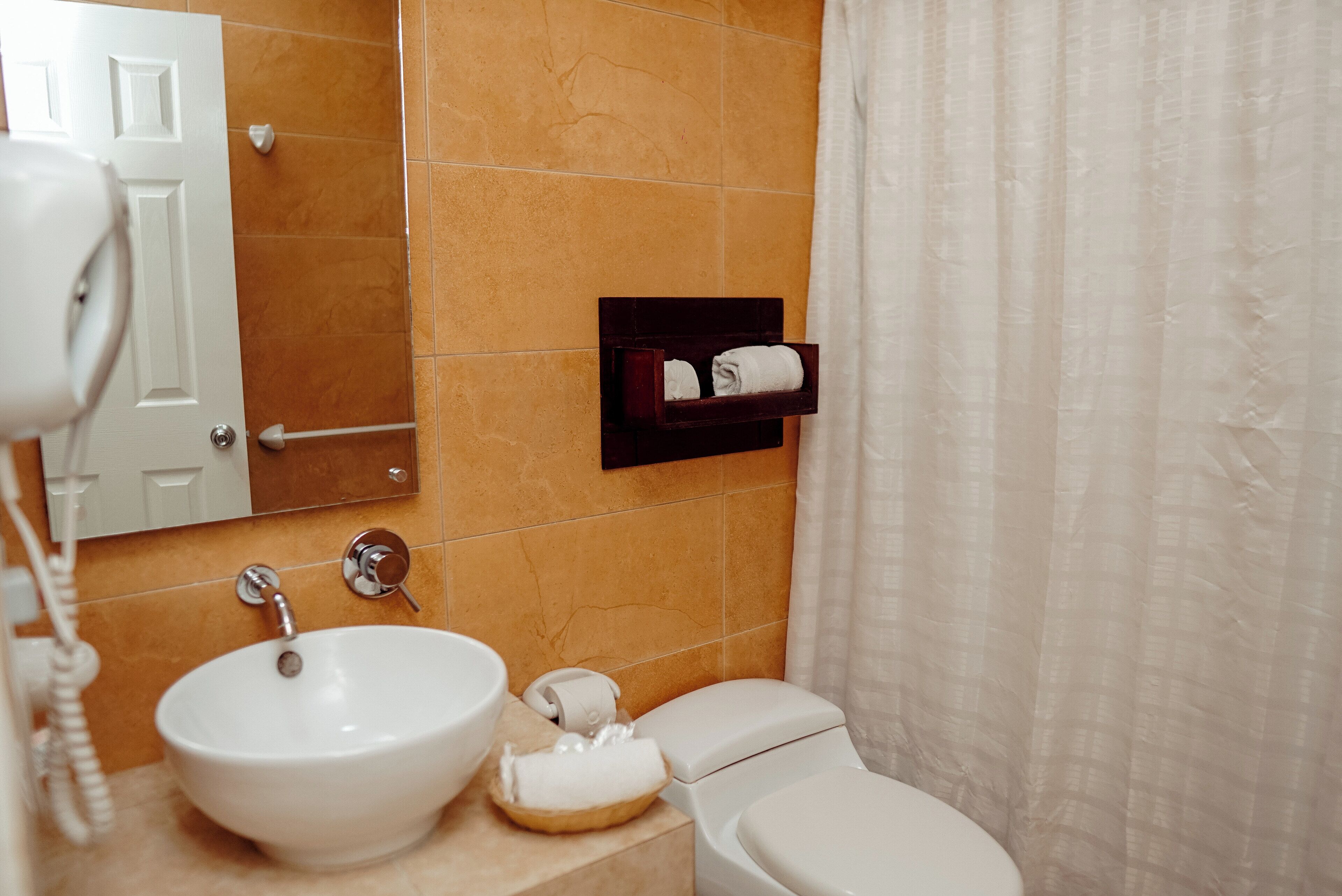 Un baño con lavamanos blanco, inodoro y toallero con toallas.