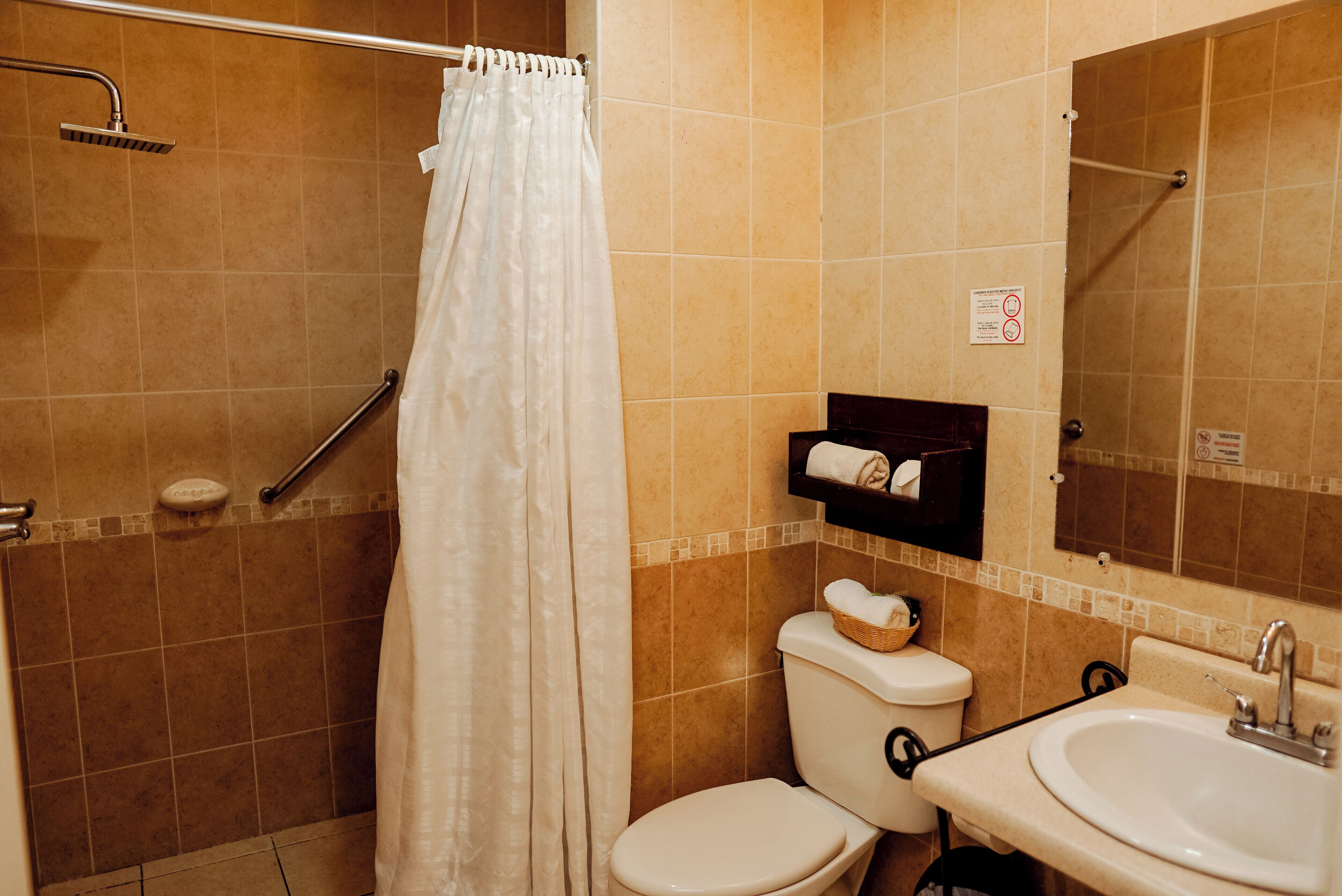 A bathroom with a shower, toilet, sink, and a towel rack.