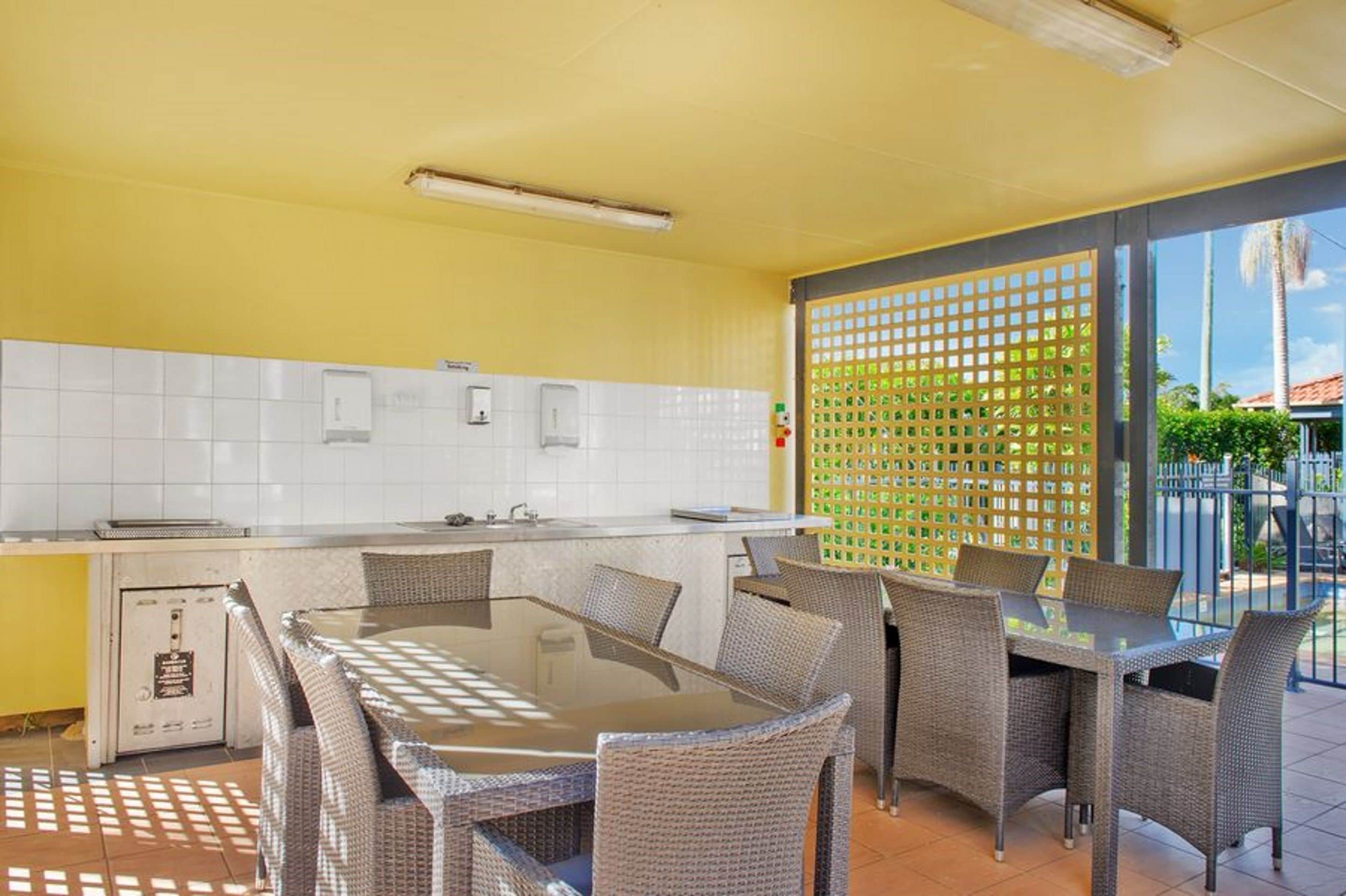 A kitchen with a dining area, white tiled backsplash, and a view of the outdoors.