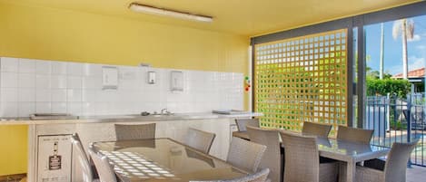 A kitchen with a dining area, white tiled backsplash, and a view of the outdoors.