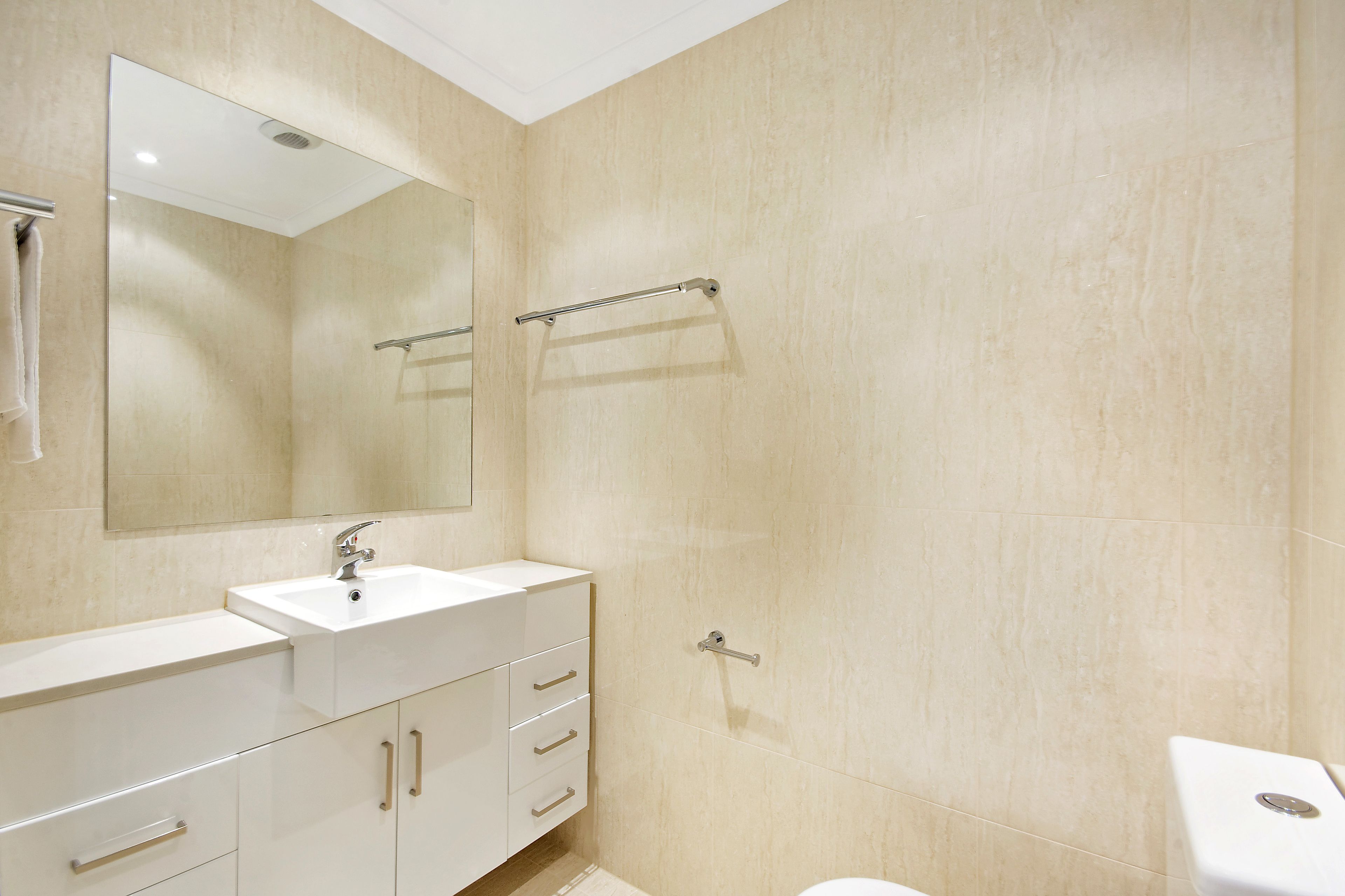 Une salle de bain moderne avec un lavabo blanc, un miroir et des toilettes.