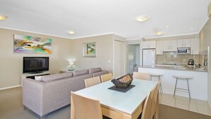 A modern apartment with a living room, dining area, and kitchenette.