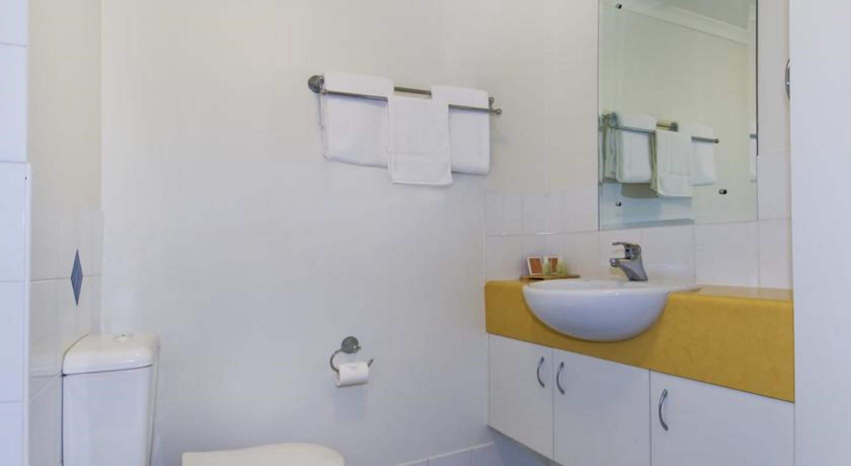 Et badeværelse med toilet, vask og spejl.
