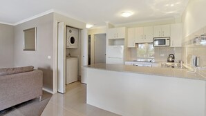 A modern kitchen with white cabinets, a built-in microwave, and a stainless steel refrigerator.