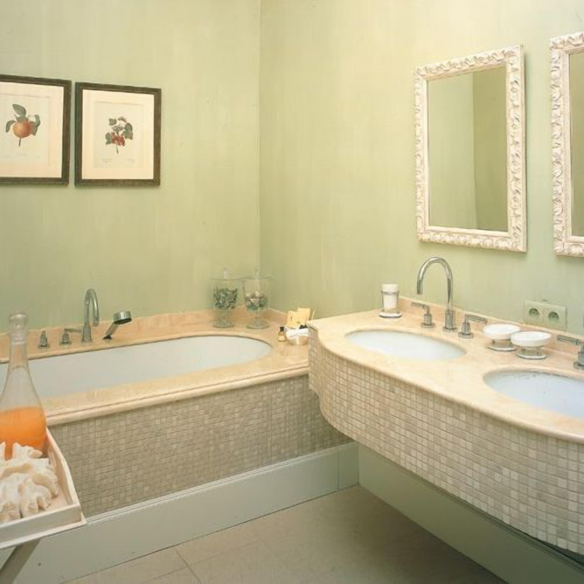 Un baño con dos lavamanos, una bañera y dos cuadros enmarcados en la pared.