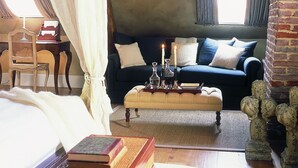 Una habitación acogedora con cama, sofá, una mesita con velas y una ventana con cortinas.
