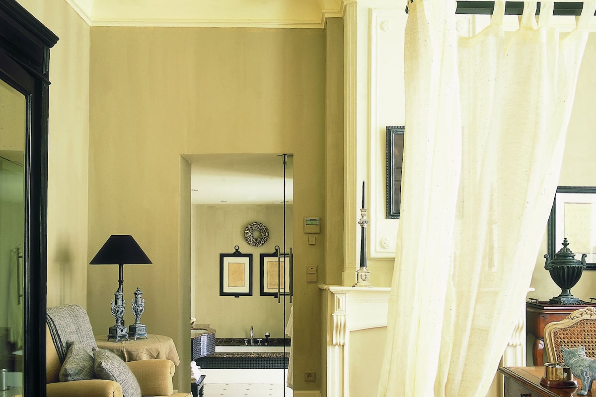 Une pièce avec un plancher en bois, un canapé, un miroir et un lit à baldaquin.