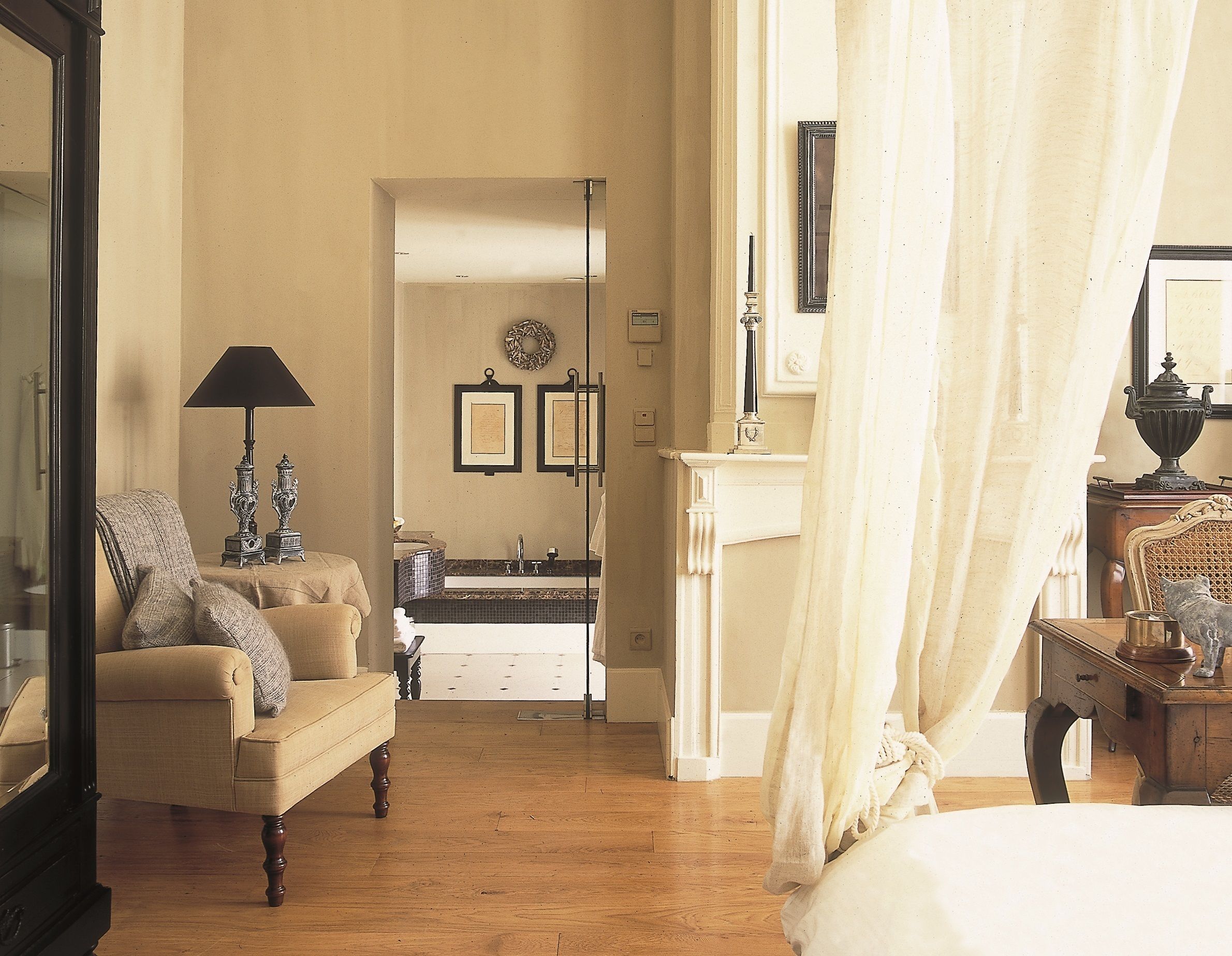 A spacious living room with a large mirror, a sofa, a lamp, and a view into the kitchen.