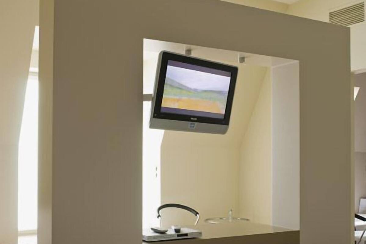 Une chambre d’hôtel équipée d’un lit, d’un bureau, d’une chaise, d’un téléviseur fixé au mur et d’une fenêtre.