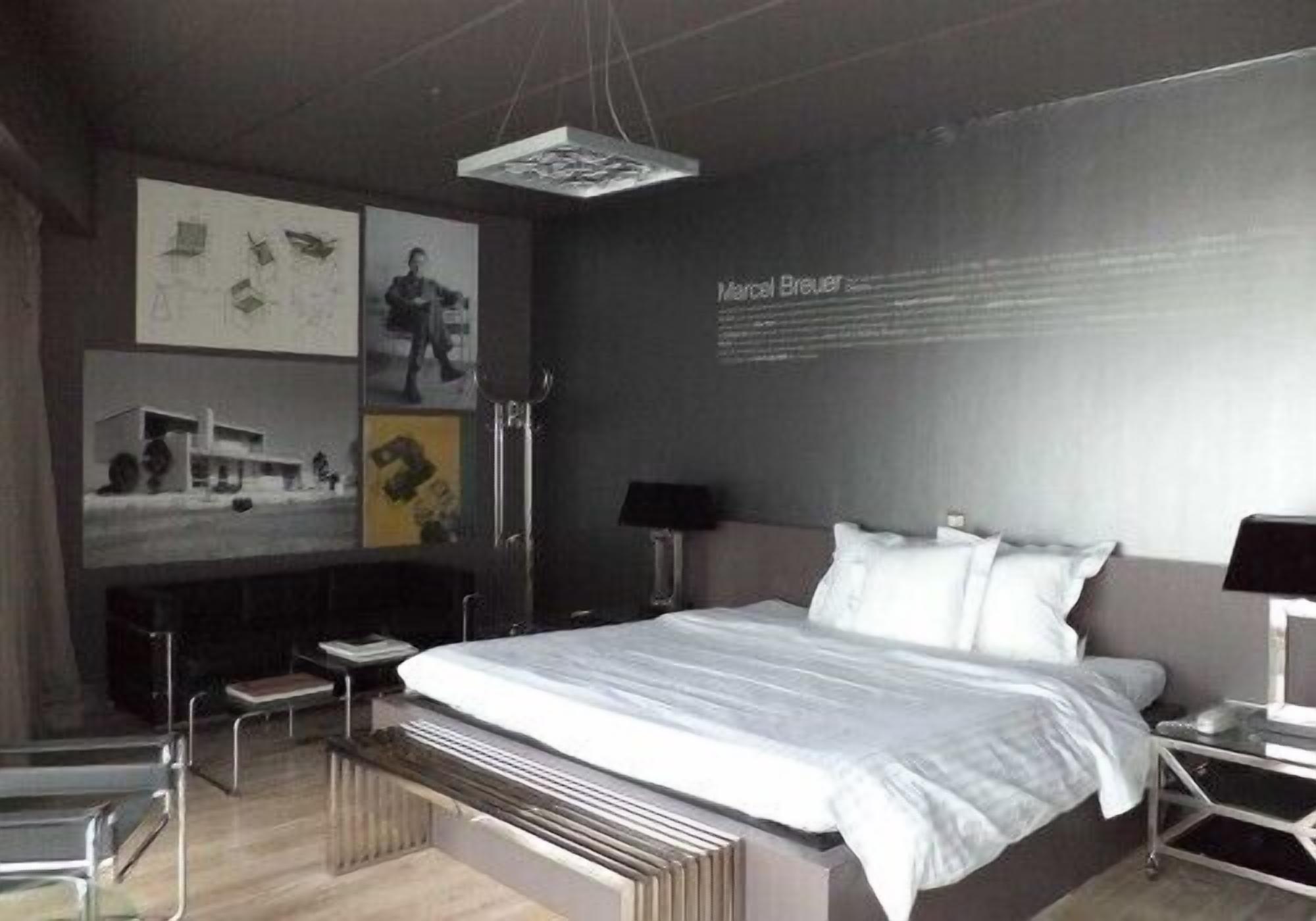 Un dormitorio moderno con una cama grande, mesitas de noche, un escritorio y obras de arte en las paredes.