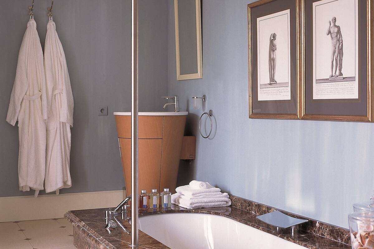 Une salle de bain moderne avec une grande baignoire, un meuble-lavabo en bois et deux tableaux encadrés au mur.