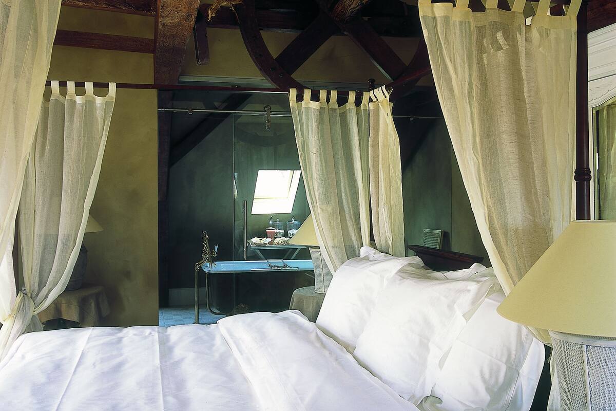 Une chambre à coucher avec un grand lit, une table de chevet, une lampe et un miroir.