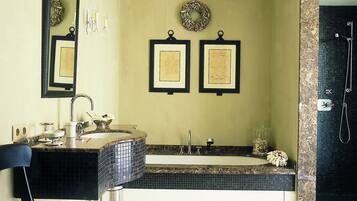 A bathroom with a large mirror, two framed certificates on the wall, a bathtub, and a shower area.