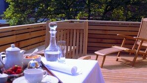 A wooden deck with a table set for a meal, a chair, and a view of trees.