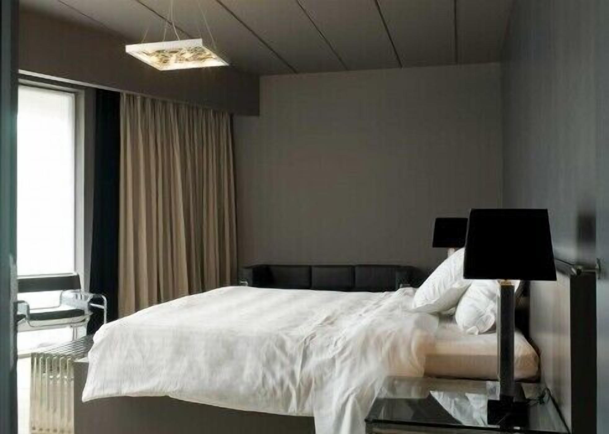 A modern hotel room with a bed, a desk, and a lamp.