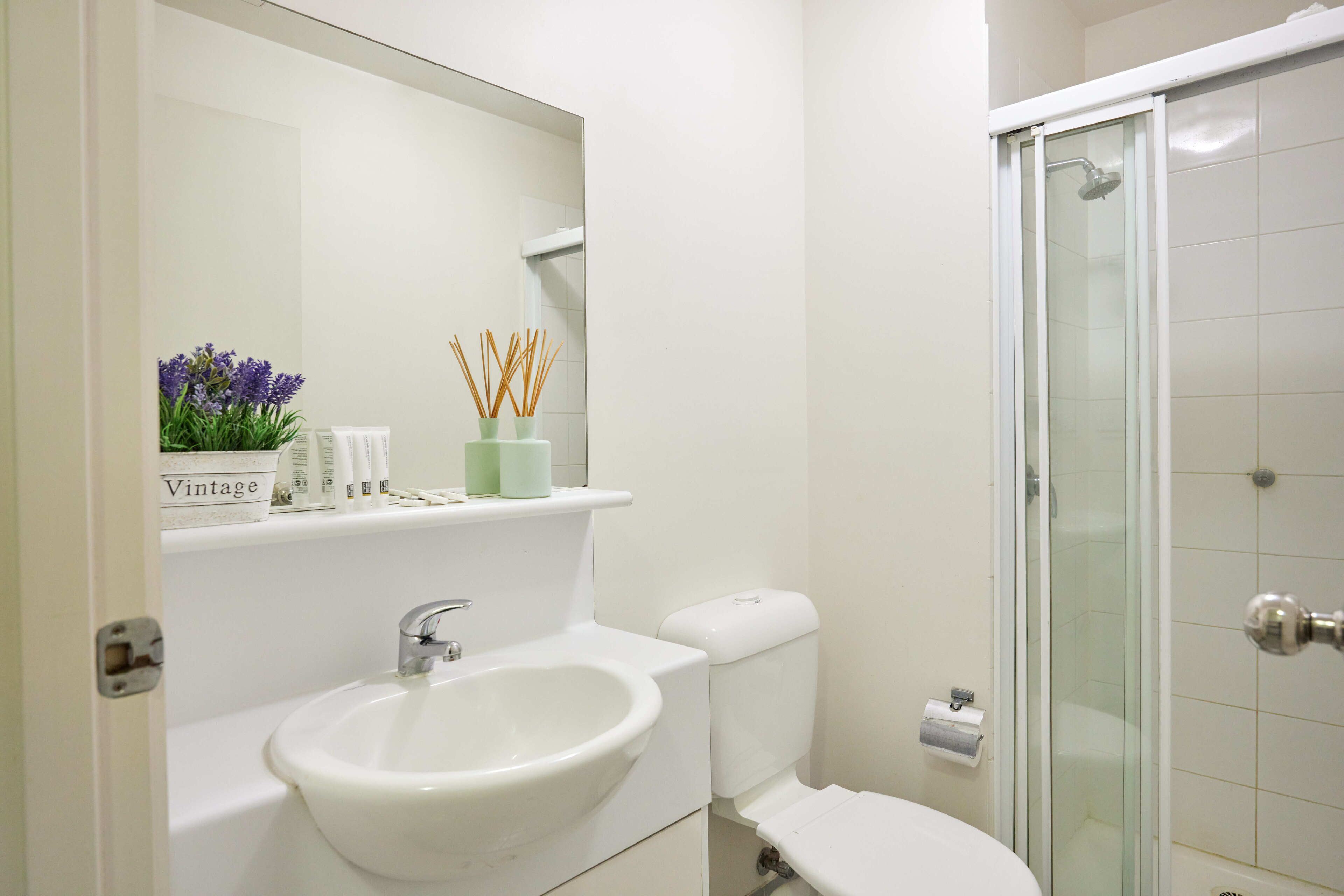 A bathroom with a white sink, toilet, and glass shower enclosure.