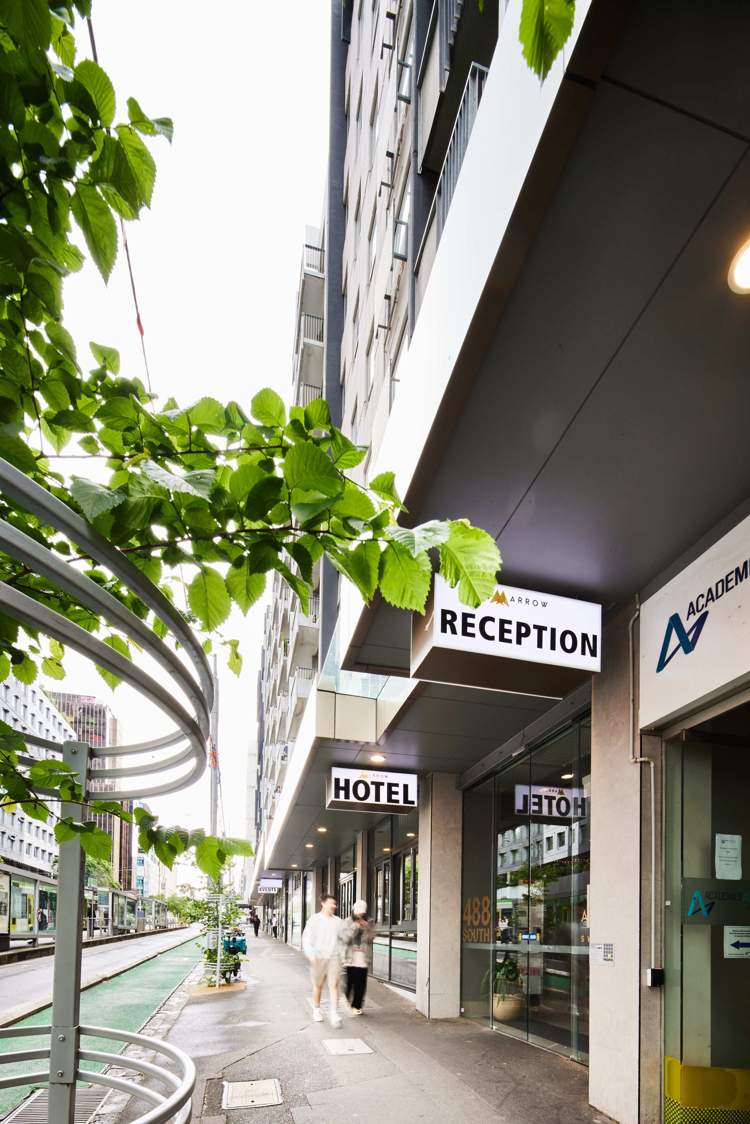 A hotel reception with a modern design, a glass facade, and a sign indicating the reception area.
