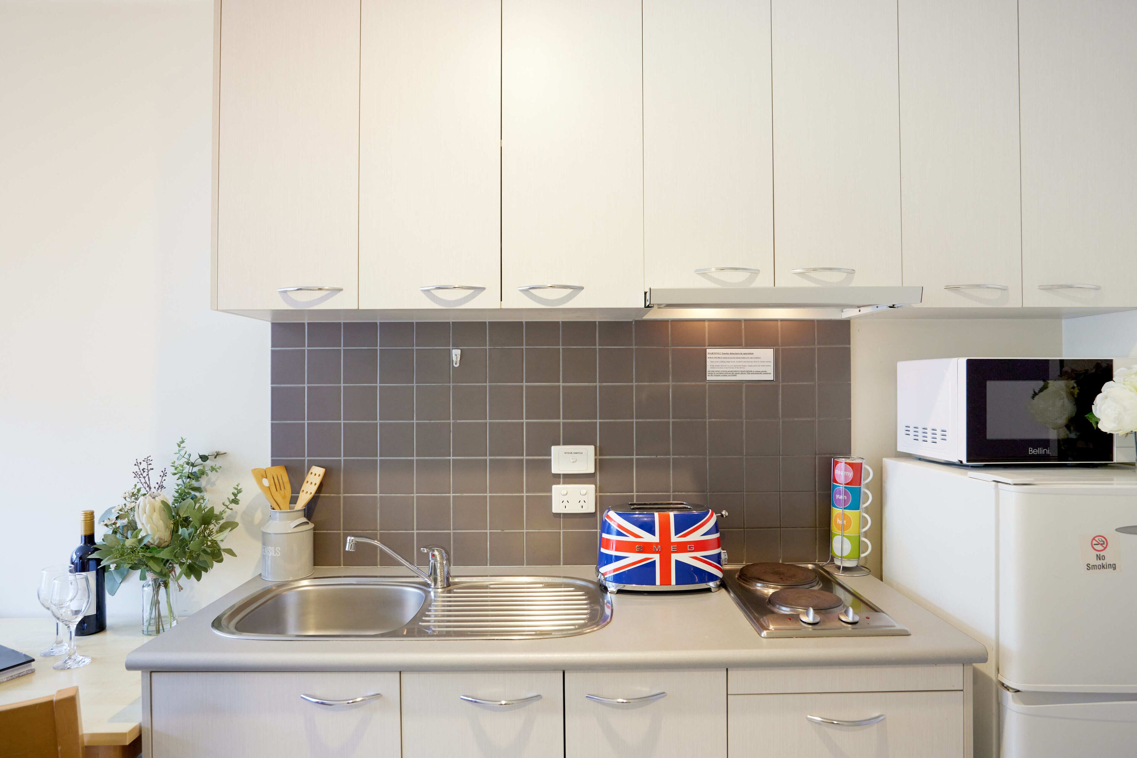 A modern kitchen with white cabinets, a stainless steel sink, a microwave, and a toaster.