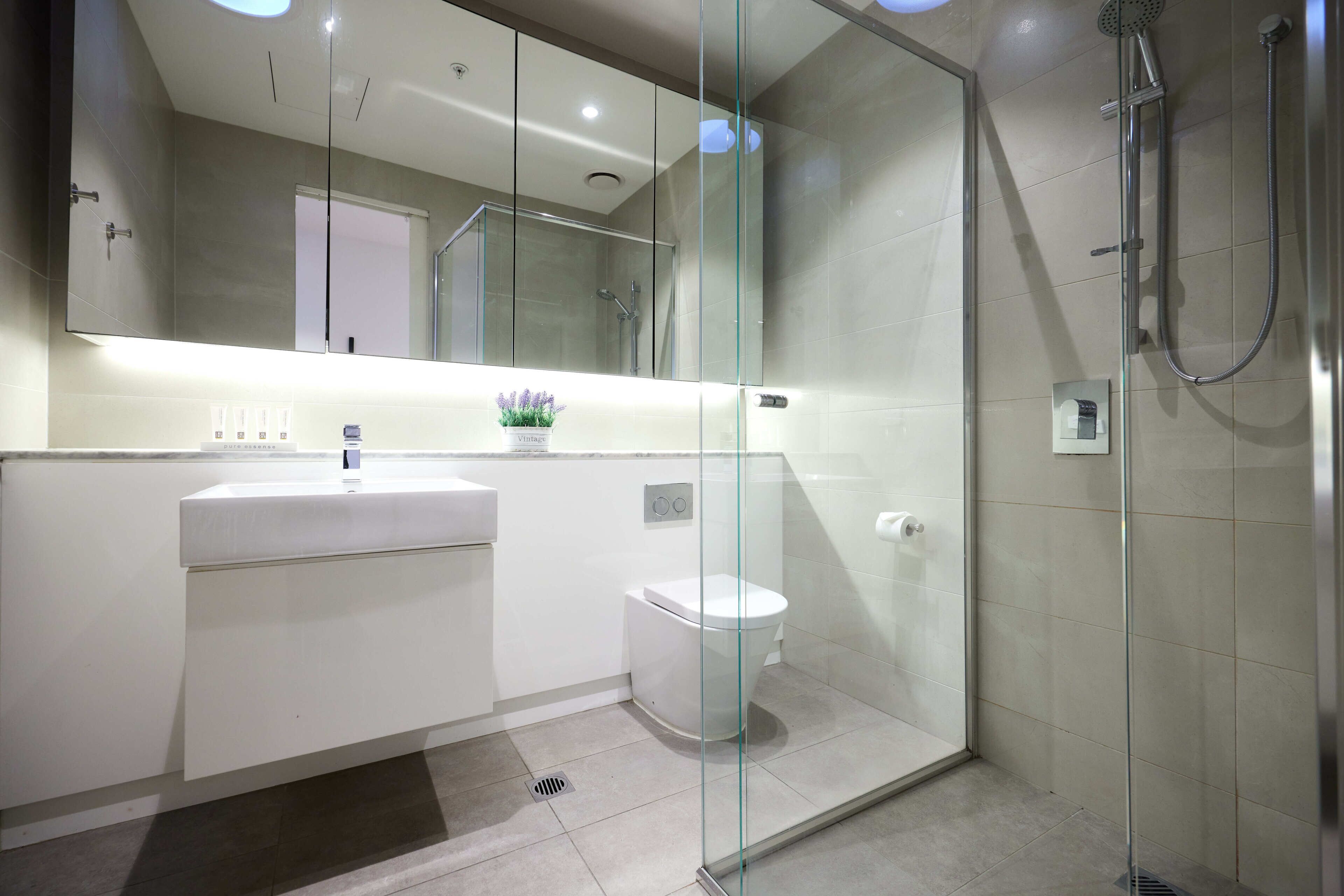A modern bathroom with a glass shower enclosure, a white sink, and a toilet.