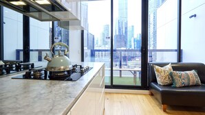 A modern kitchen with a large window, a stove, and a sofa with cushions.