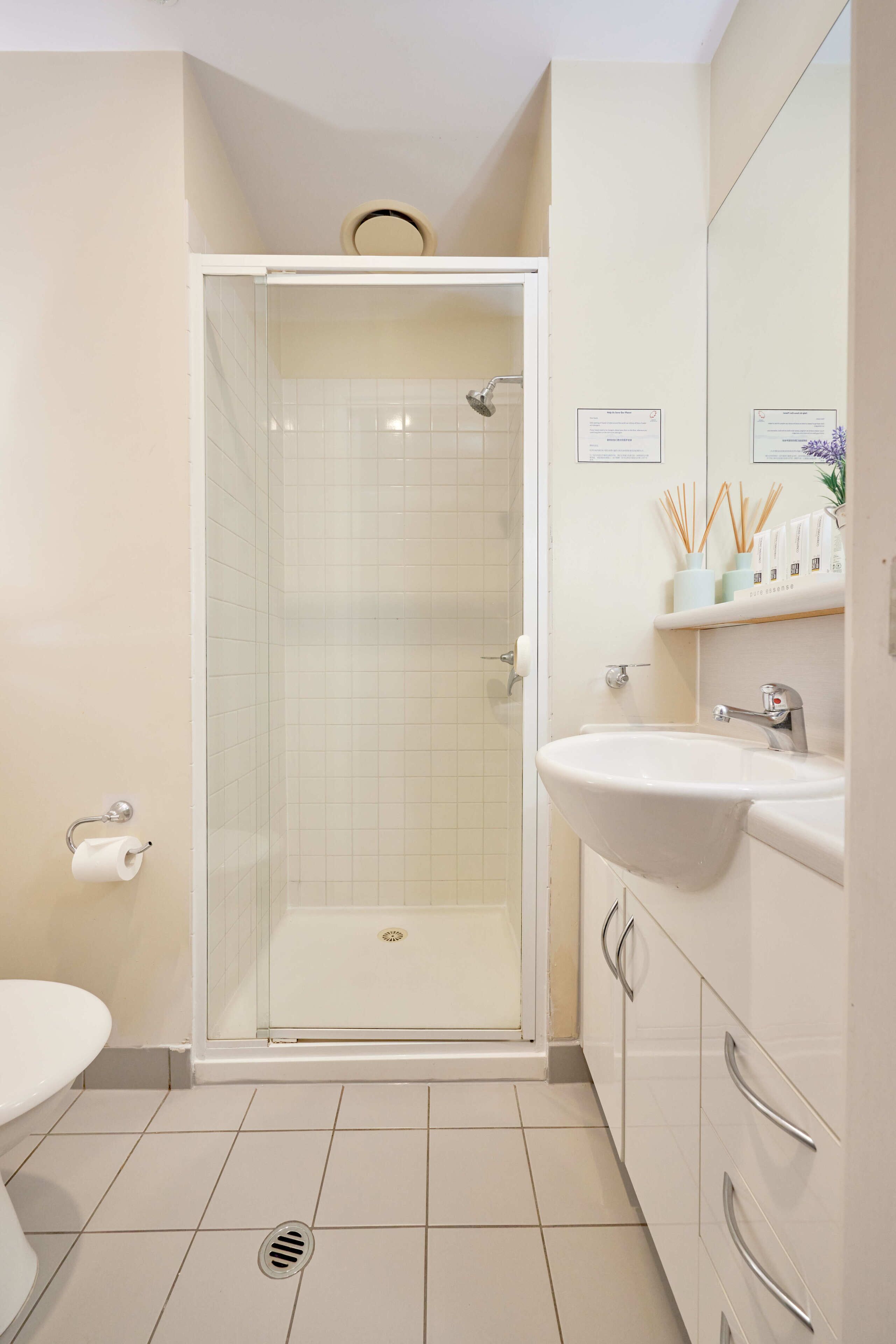 A bathroom with a glass-enclosed shower, a white sink, and a toilet.