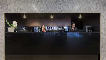 Una recepción con mostrador oscuro, armarios de madera y una planta en maceta.