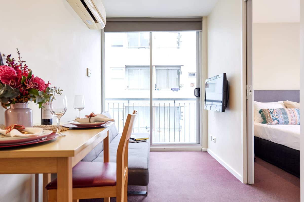 Una habitación de hotel compacta con comedor, cama y televisor.