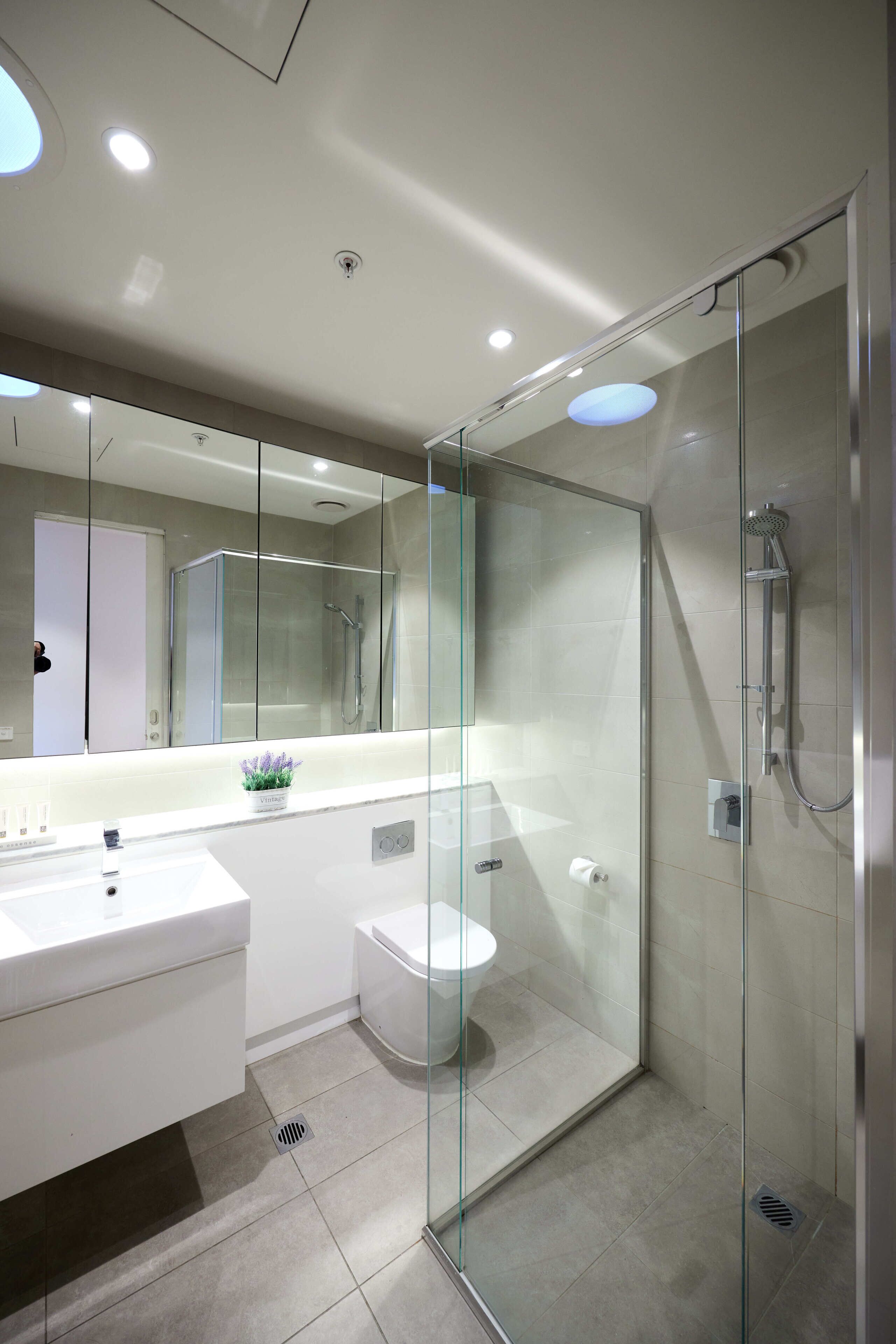 A modern bathroom with a glass-enclosed shower, a white sink, and a toilet.