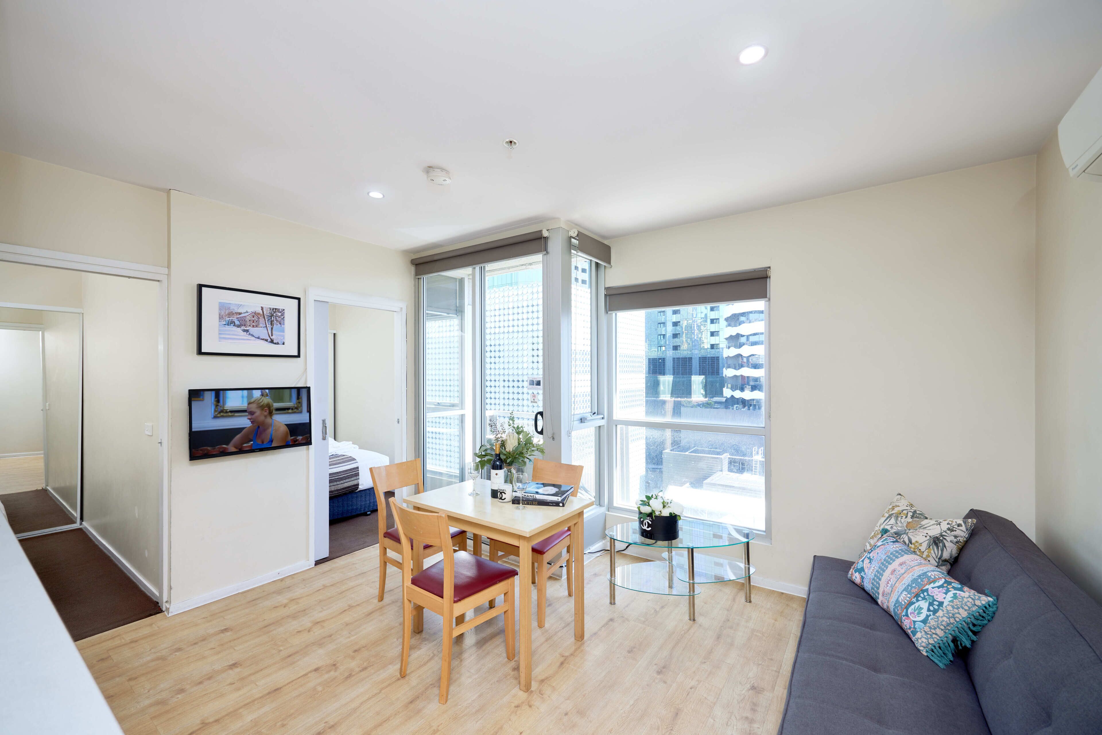 A modern apartment with a dining area, a sofa, and a balcony with a city view.