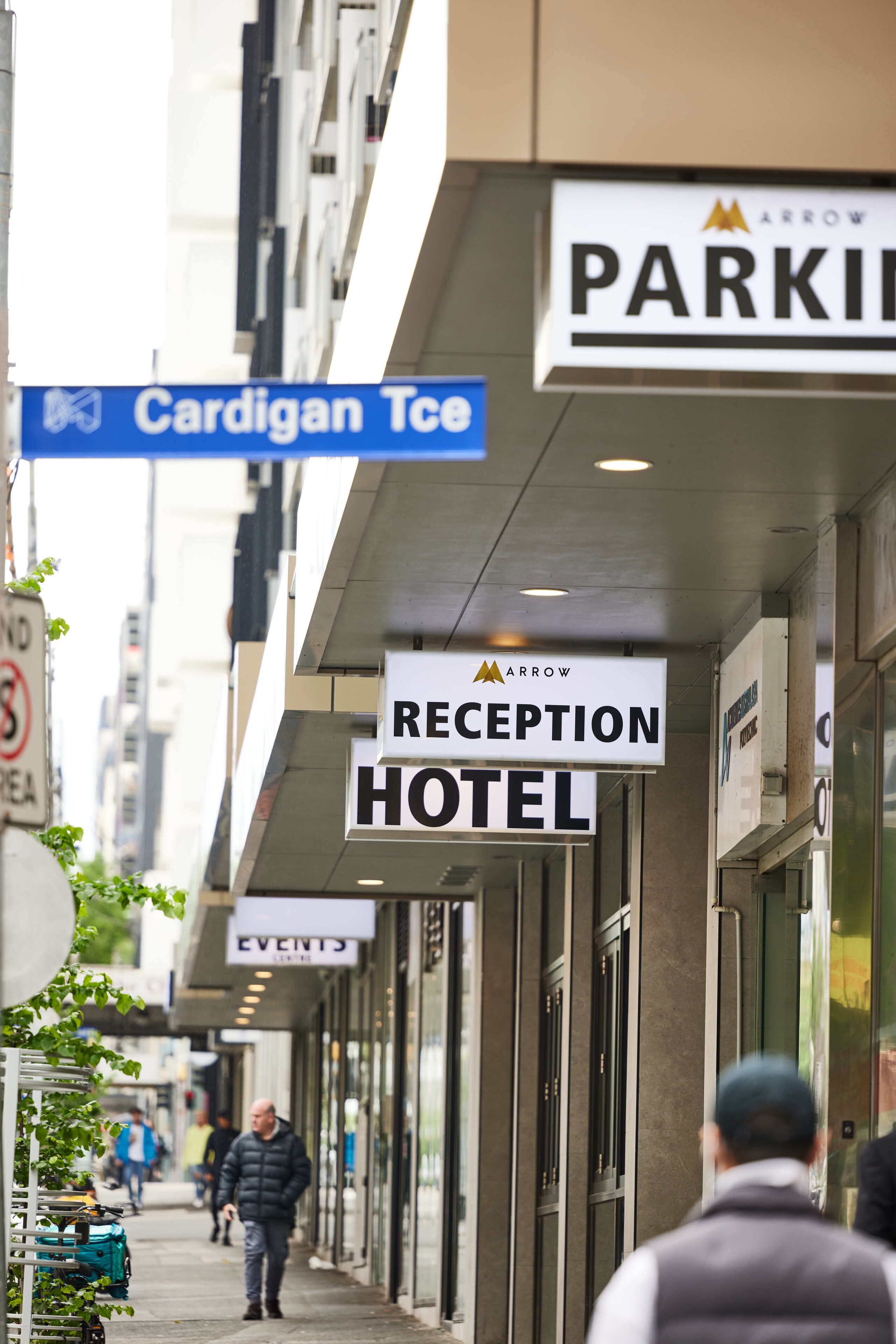 Een hotel receptie met borden waarop 'Cardigan Tce' en 'Arrow Reception Hotel' staan.