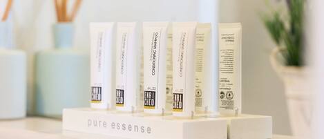 A display of 'pure essence' hair care products on a white shelf.