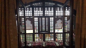 A room with a traditional window design, featuring a patterned mat and a view of the outdoors. - Ali Baba Hotel (Dahab)