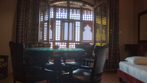 A room with a round table, four chairs, a bed, and a window with intricate lattice design. - Ali Baba Hotel (Dahab)