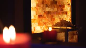 Una pared de piedra con chimenea y una mesa con vela.