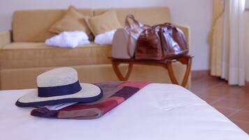 A bed with a hat and a book, a wooden chair, and a beige sofa in the background.