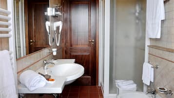A bathroom with two sinks, a hairdryer, and a shower.