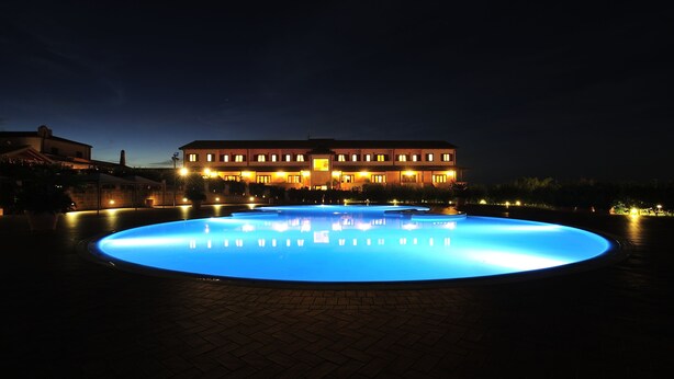 A large building with a swimming pool at night, illuminated by artificial lighting. - Popilia Country Resort (Maierato)