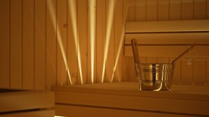 A sauna with a wooden bench and a metal bucket with a wooden handle. - Popilia Country Resort (Maierato)