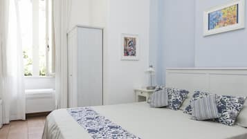 A bedroom with a bed, a nightstand, a lamp, and two framed artworks on the wall.