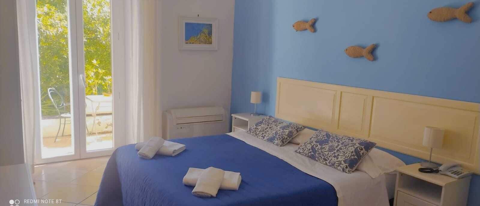 A bedroom with a bed, pillows, a nightstand, a lamp, and a picture on the wall.