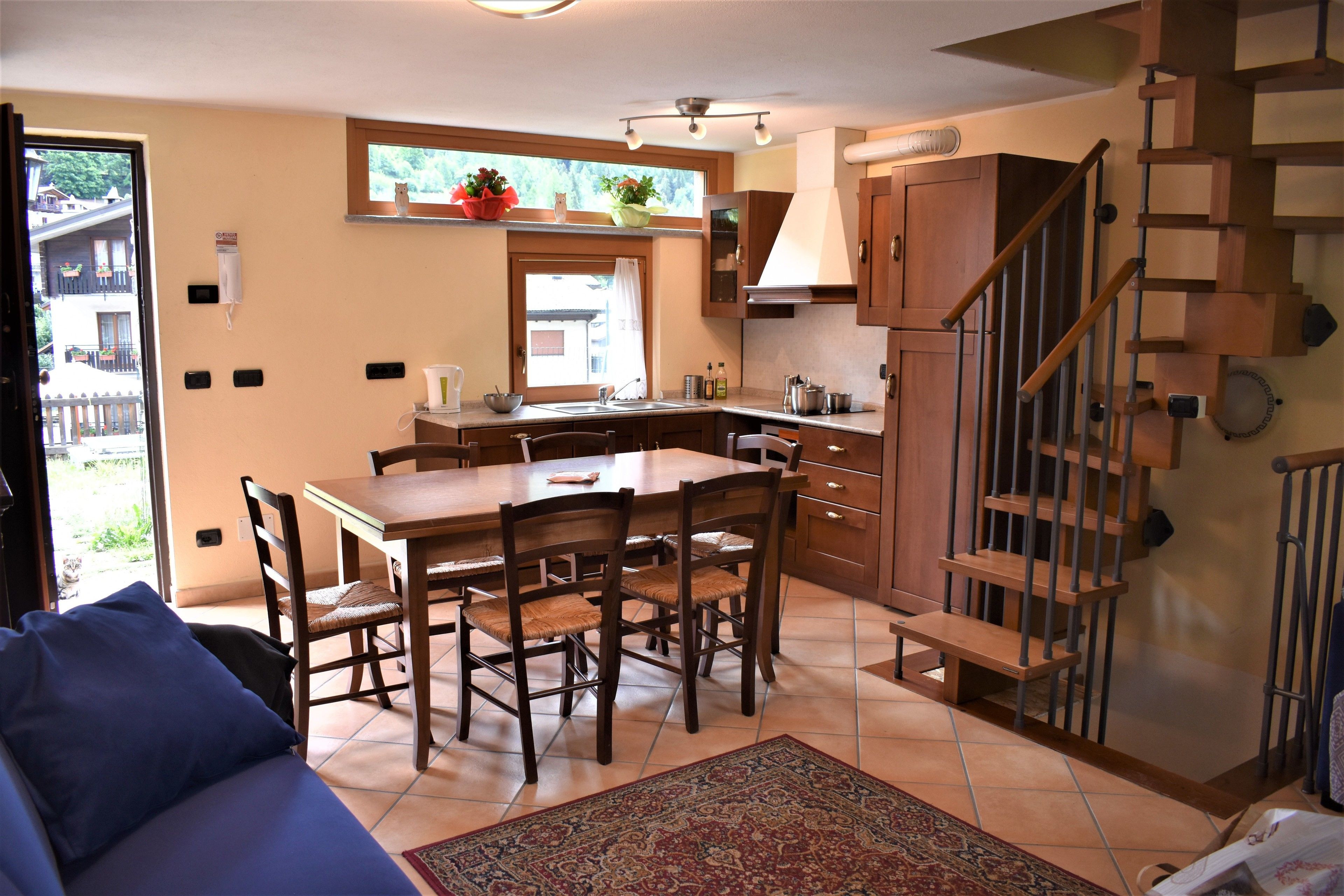 A kitchen with a dining table, chairs, and a staircase.