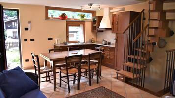 A kitchen with a dining table, chairs, and a staircase.