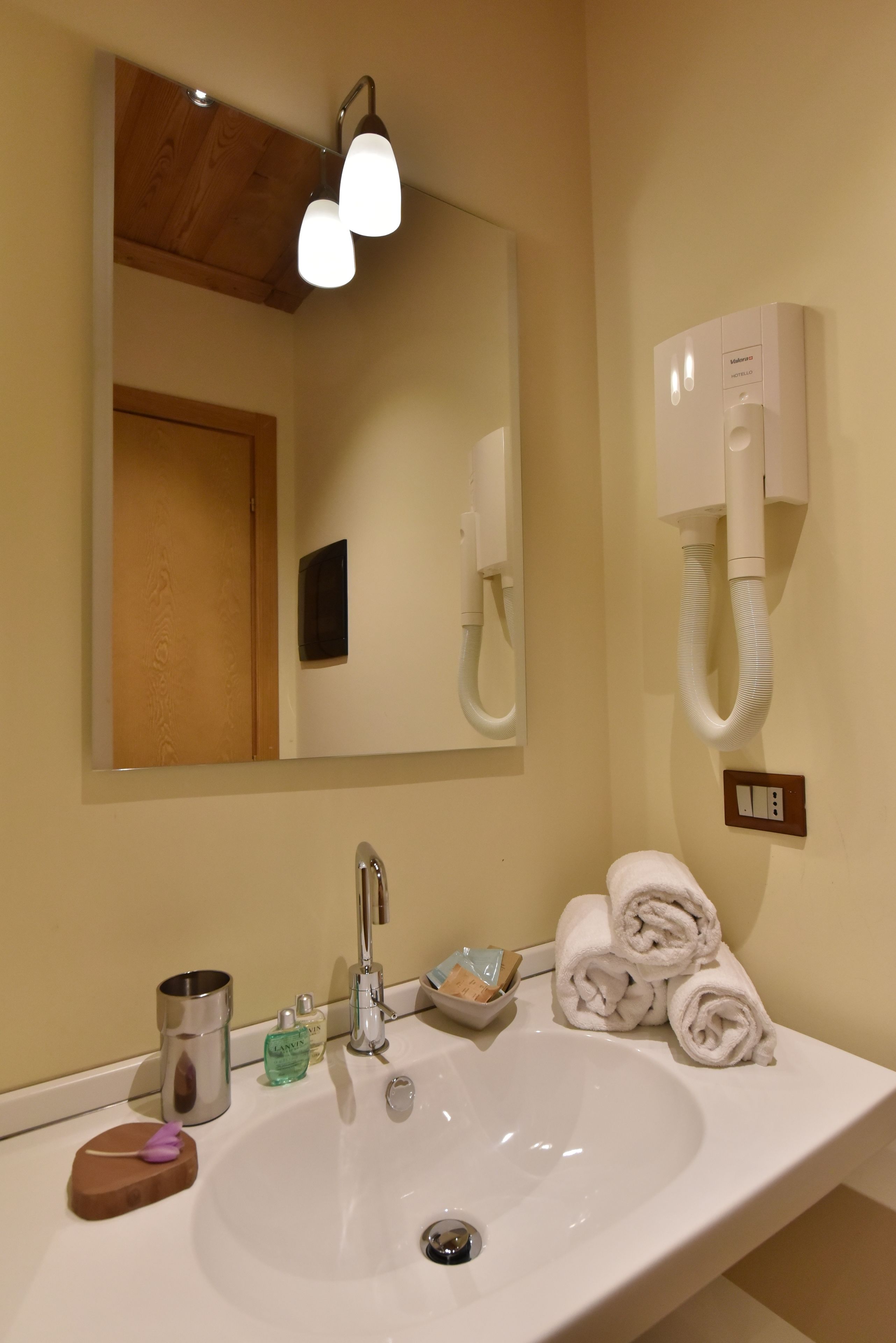 A bathroom with a sink, mirror, towel rack, and a hand dryer.