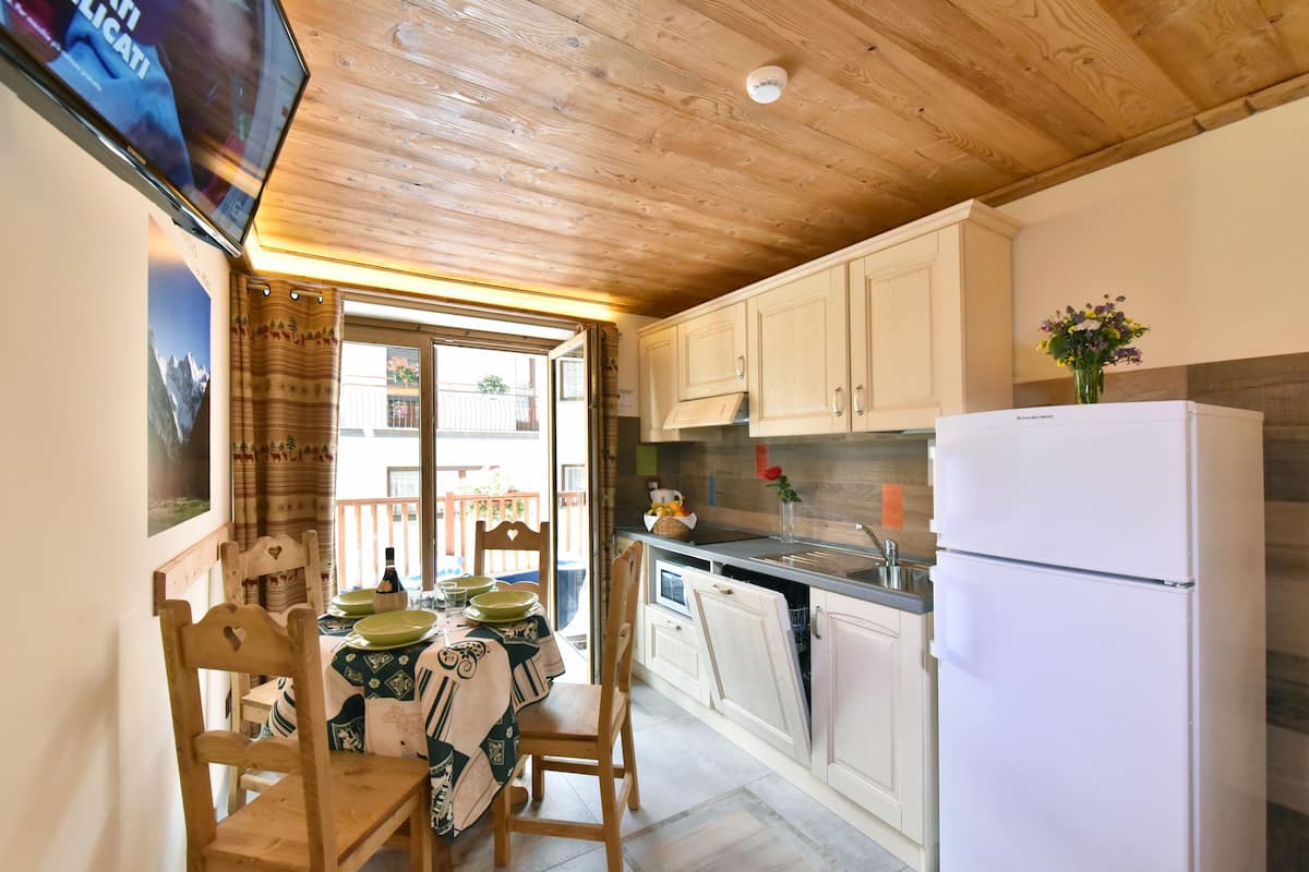 A kitchen with wooden cabinets, a refrigerator, and a dining area with a table and chairs.