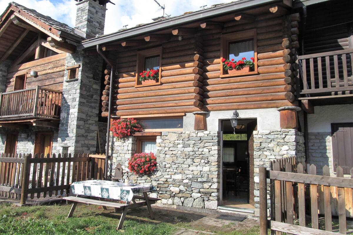 A log cabin with stone walls, wooden balconies, and flower boxes.