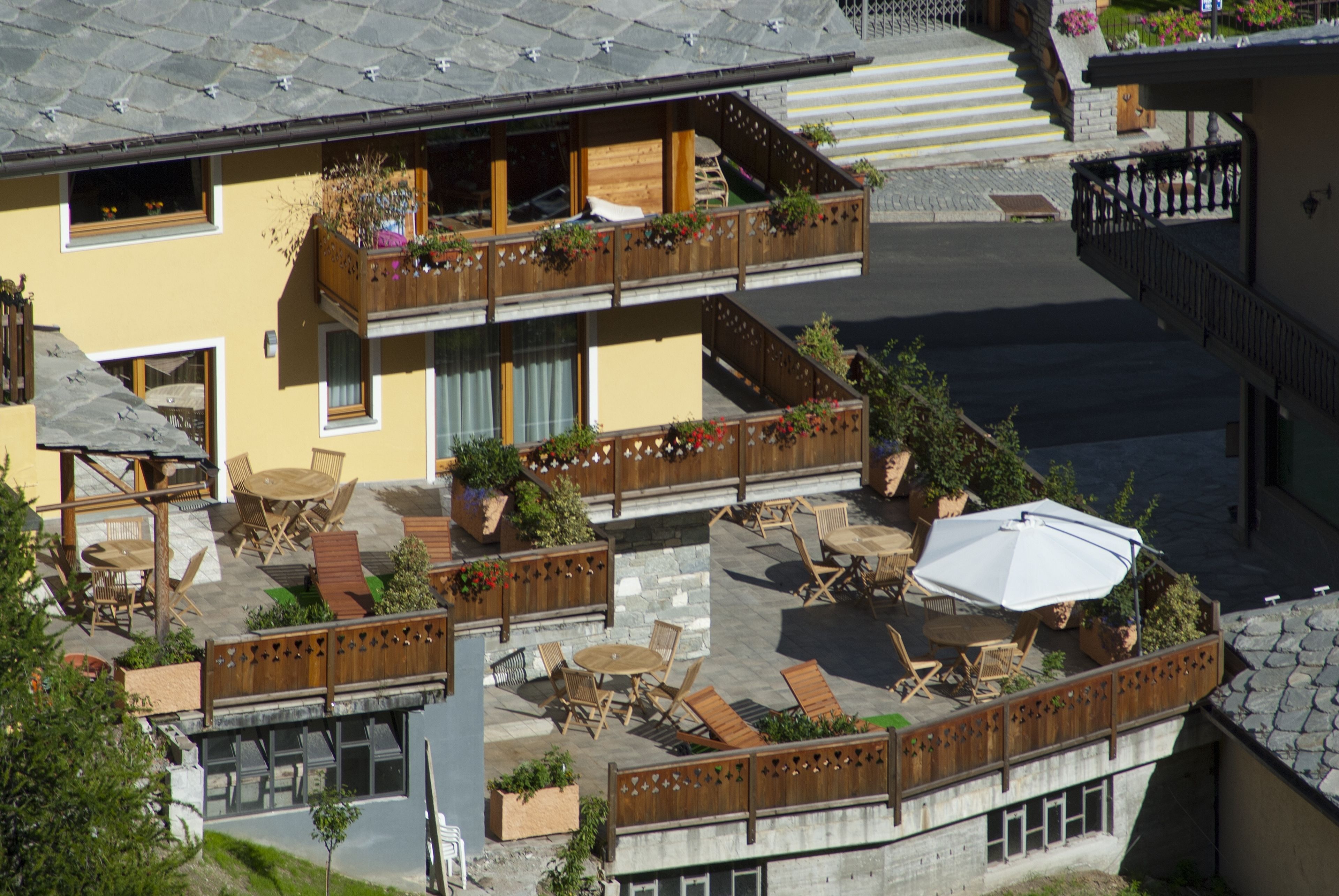 Un edificio de varios pisos con terrazas al aire libre, barandales de madera y macetas con plantas.