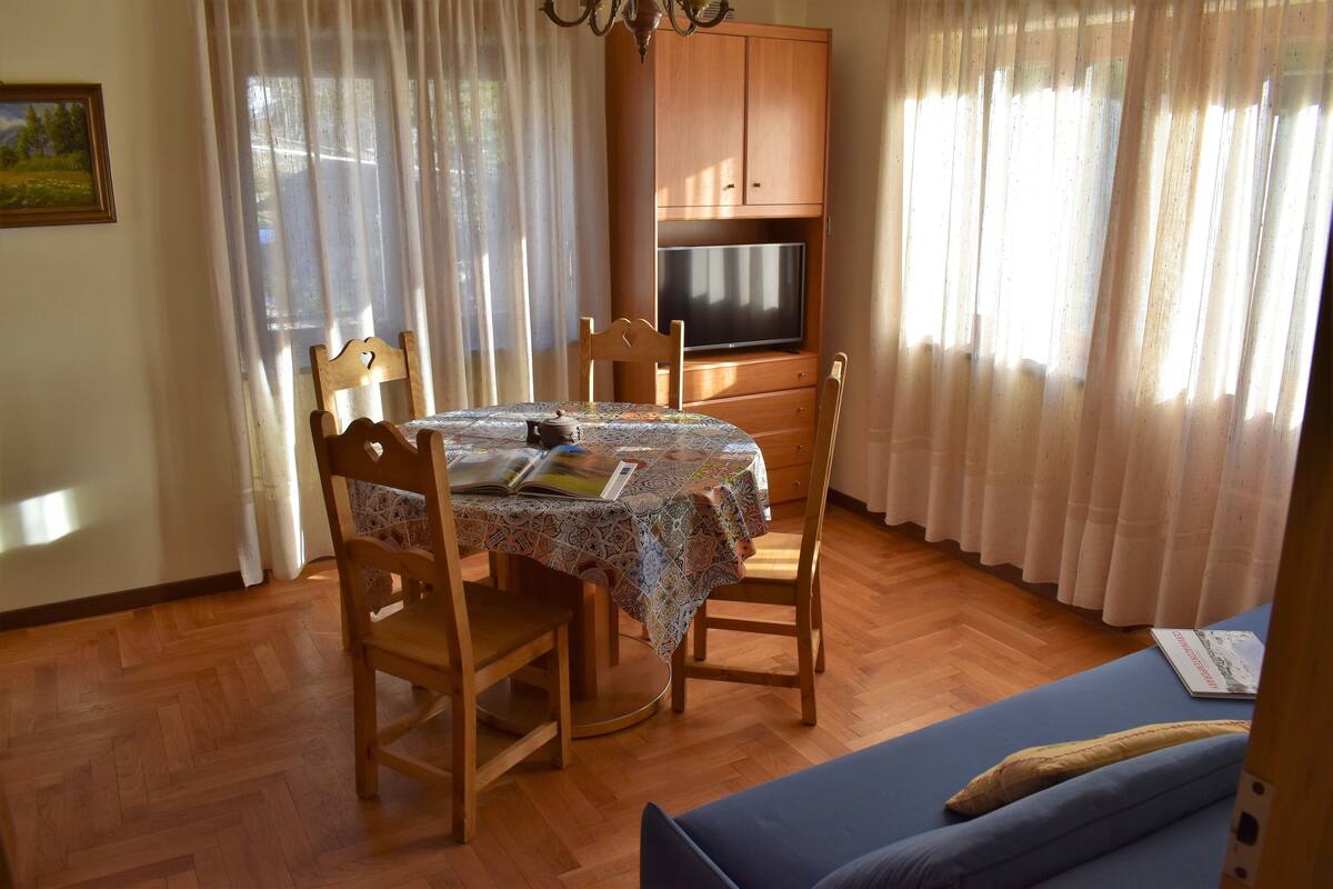 A dining area with a table, chairs, and a television above it.