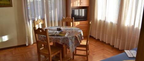 A dining area with a table, chairs, and a television above it.